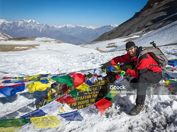 Trekker hanging the prayer flag at the Thorang La Pass Welcome Board