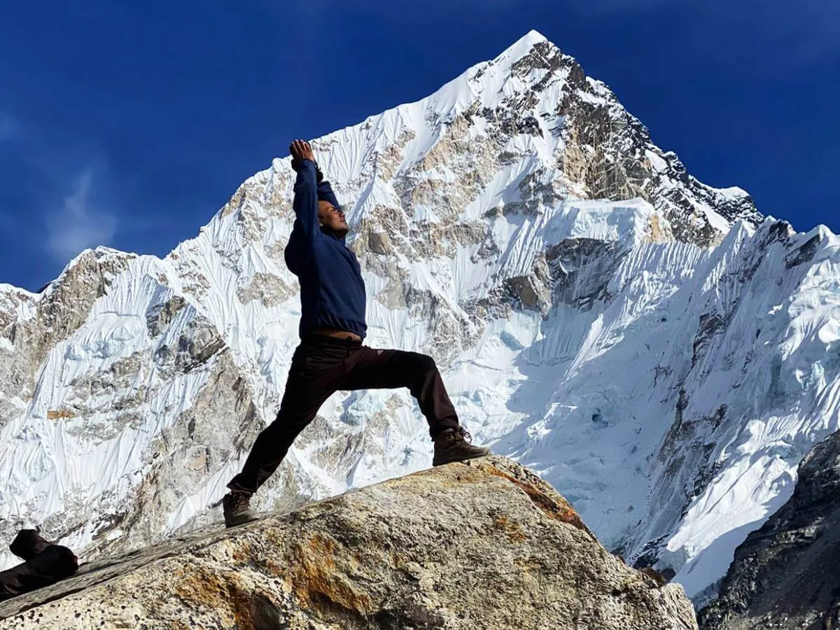 Trekker practicing yoga on a rock with Mount Everest in the background
