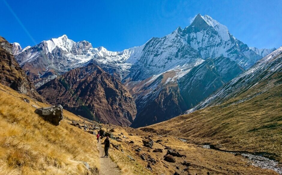 Trekkers walking along the Annapurna Base Camp trek route with mountain views in the background.