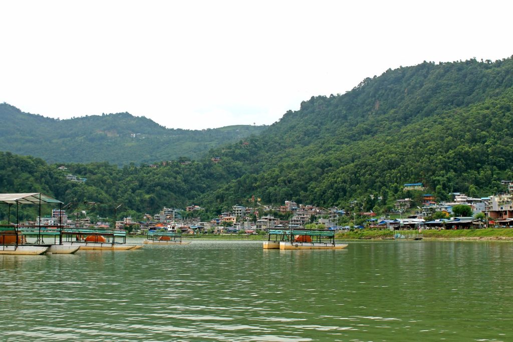 Phewa Lake in Pokhara with colorful boats and the Annapurna mountain range in the background.