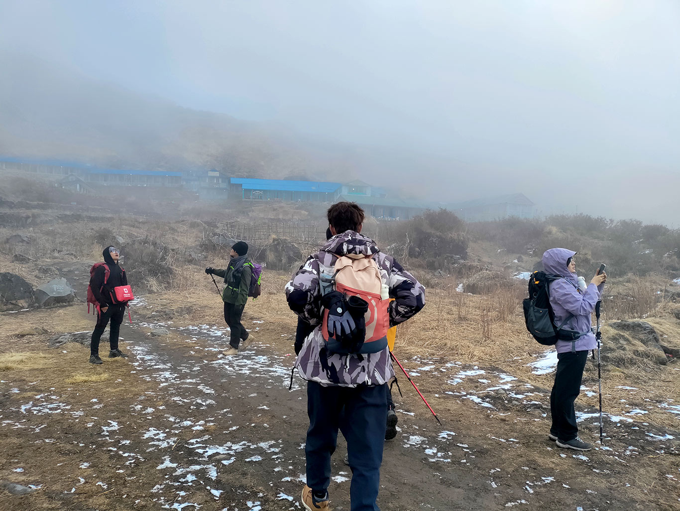 Trekkers walking near Machapuchare Base Camp with mountain peaks in the background.