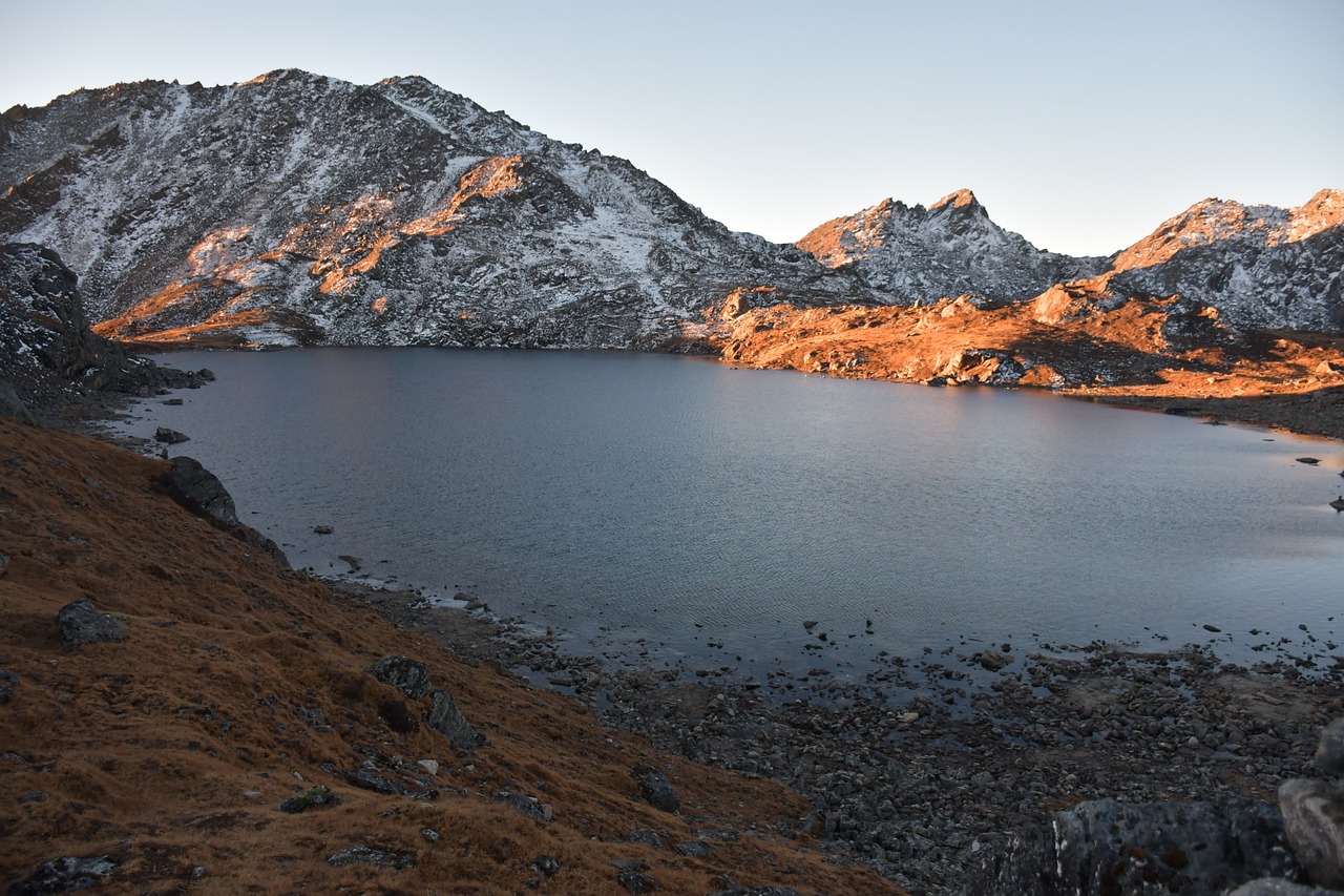 Elevated view of Gosaikunda Lake's azure waters surrounded by rugged mountains with patches of snow.