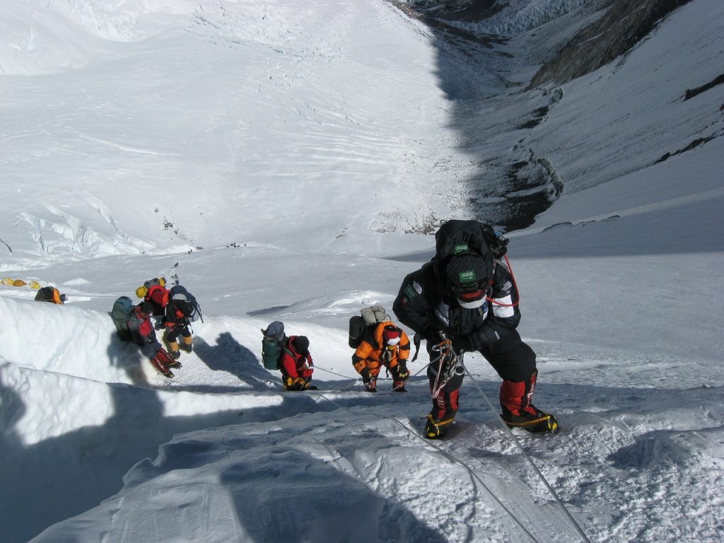 Trekkers ascending Mount Everest using ropes for support on the challenging terrain.