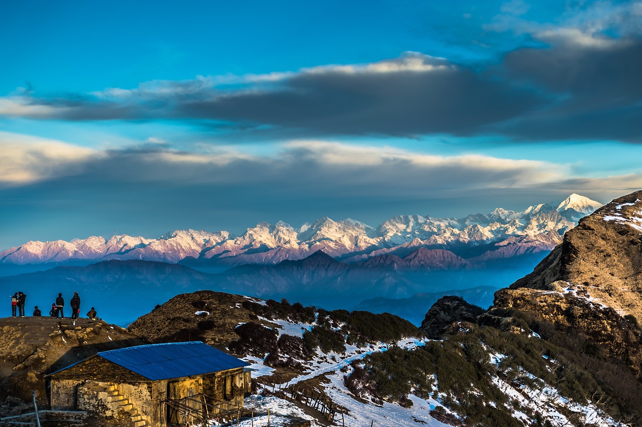 Panoramic view of the Himalayan mountain range with rolling green hills in the foreground.