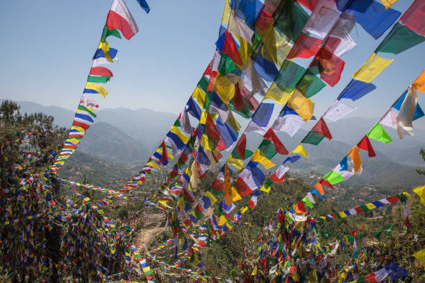 Colorful prayer flags fluttering in the wind on Dhulikhel Hills with mountain backdrop.