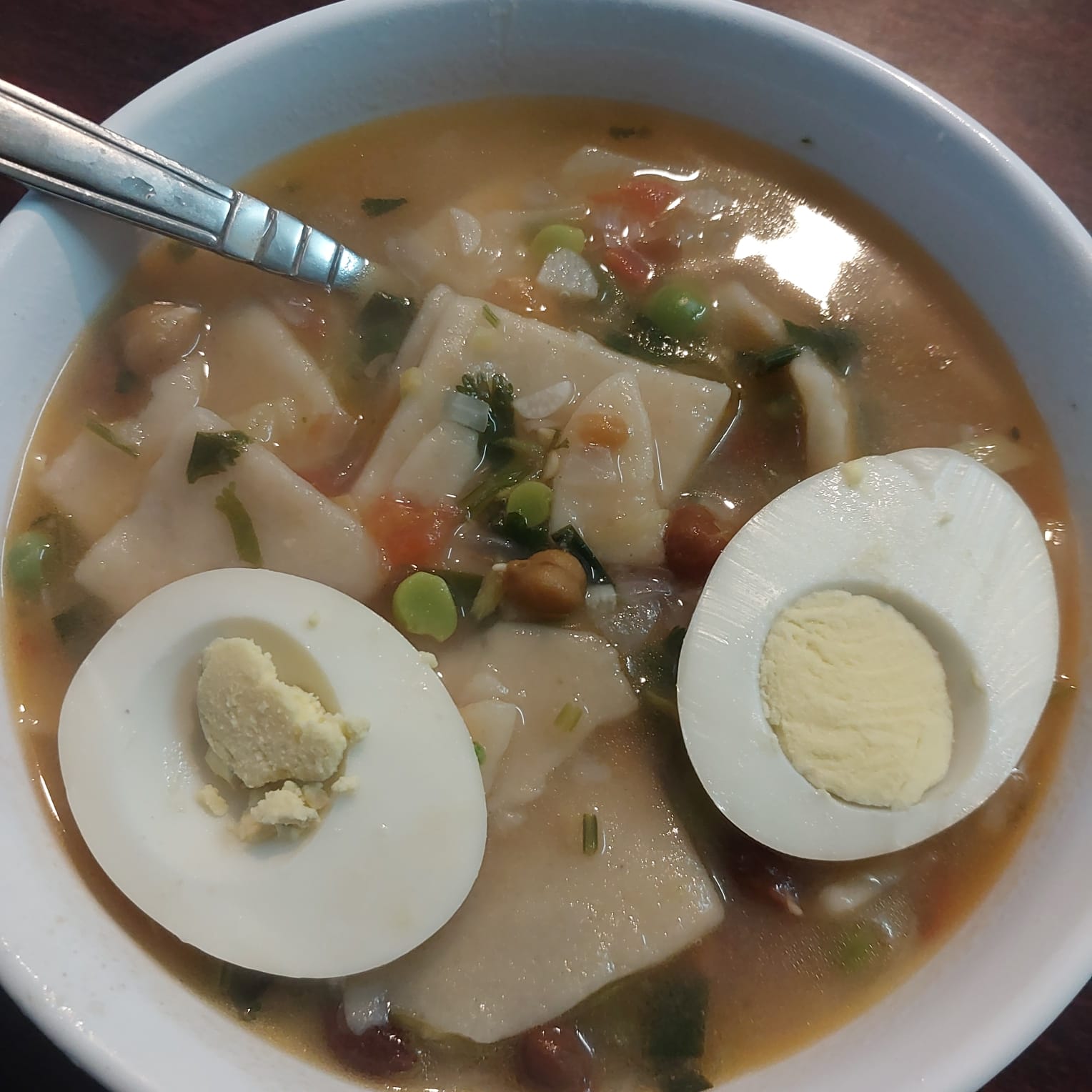  A plate of Rheldok, a Tibetan dish featuring steamed dough, vegetables, and meat, served in a rustic bowl.