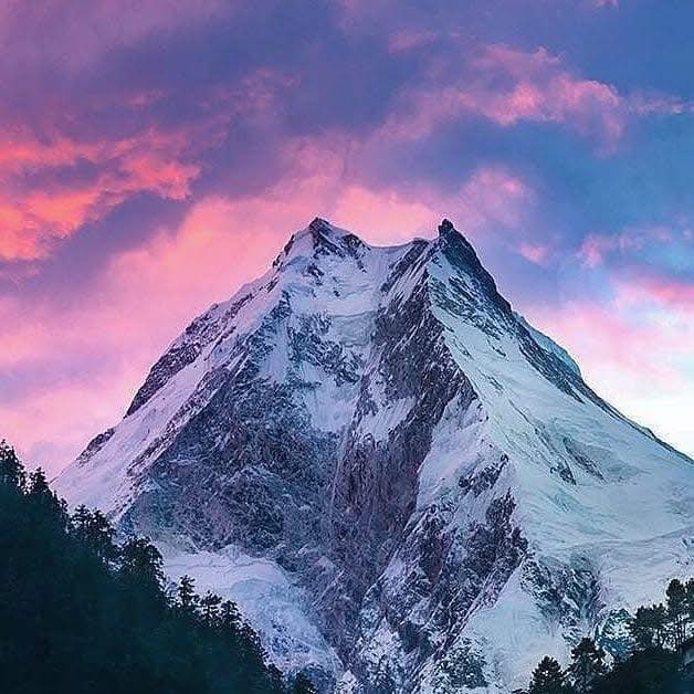 As the sun rises, golden light touches the snowy peak of Mt. Manaslu, creating a calm and breathtaking scene in the Himalayas.