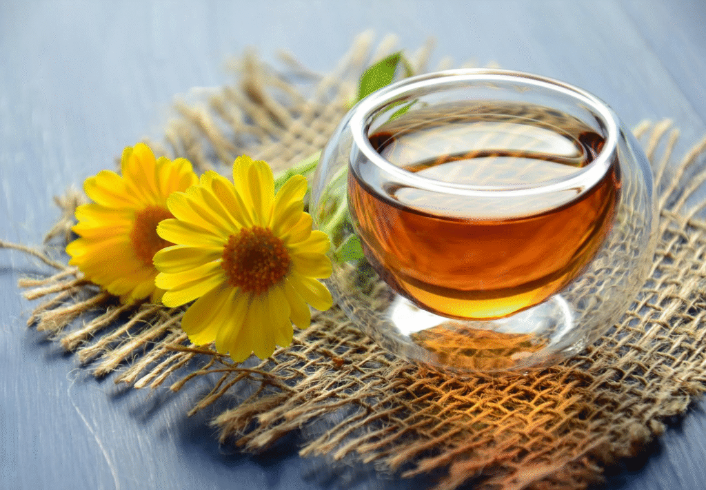 A steaming cup of tea in a clear glass cup with a saucer.