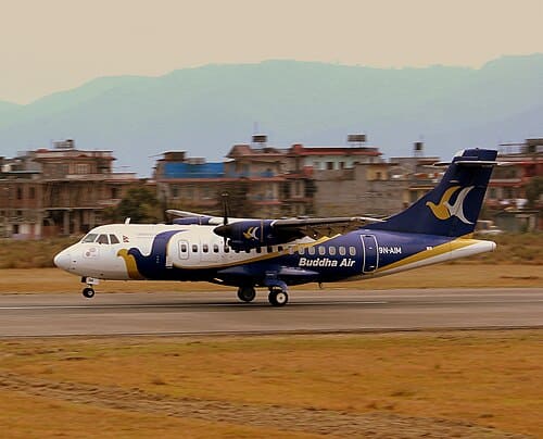 Buddha Air aircraft landing at a Nepal airport with mountains in the background