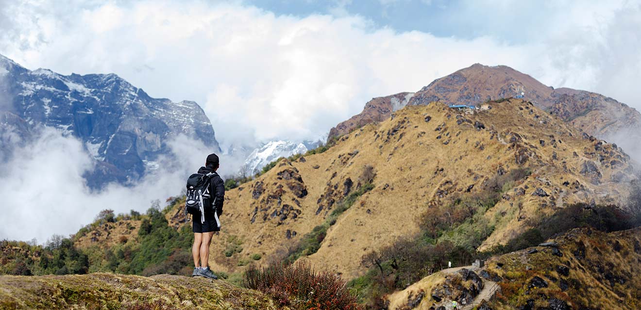 Trekker posing with the majestic Mt. Manaslu in the background during a high-altitude adventure.